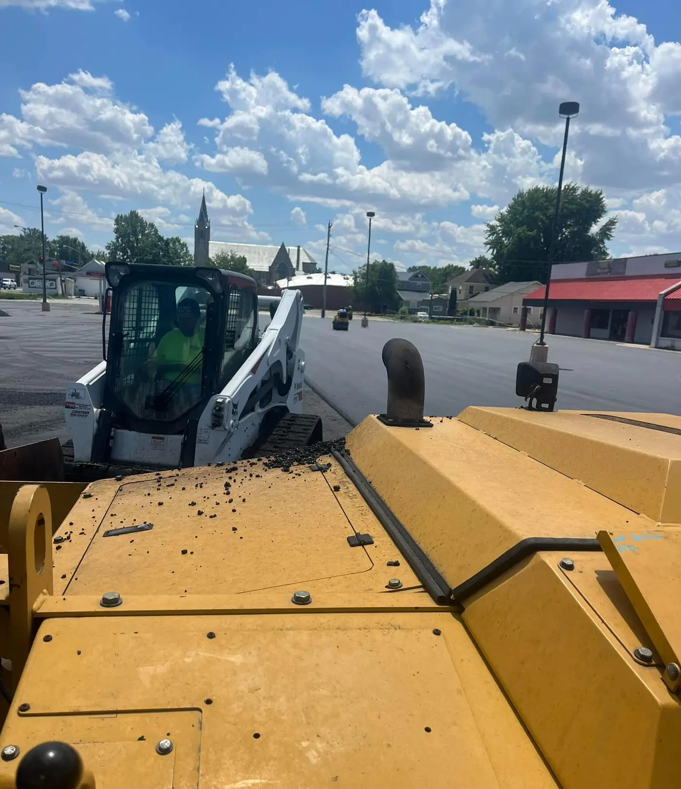 Cooper Asphalt paver and skid steer laying hot mix asphalt on a commercial approach