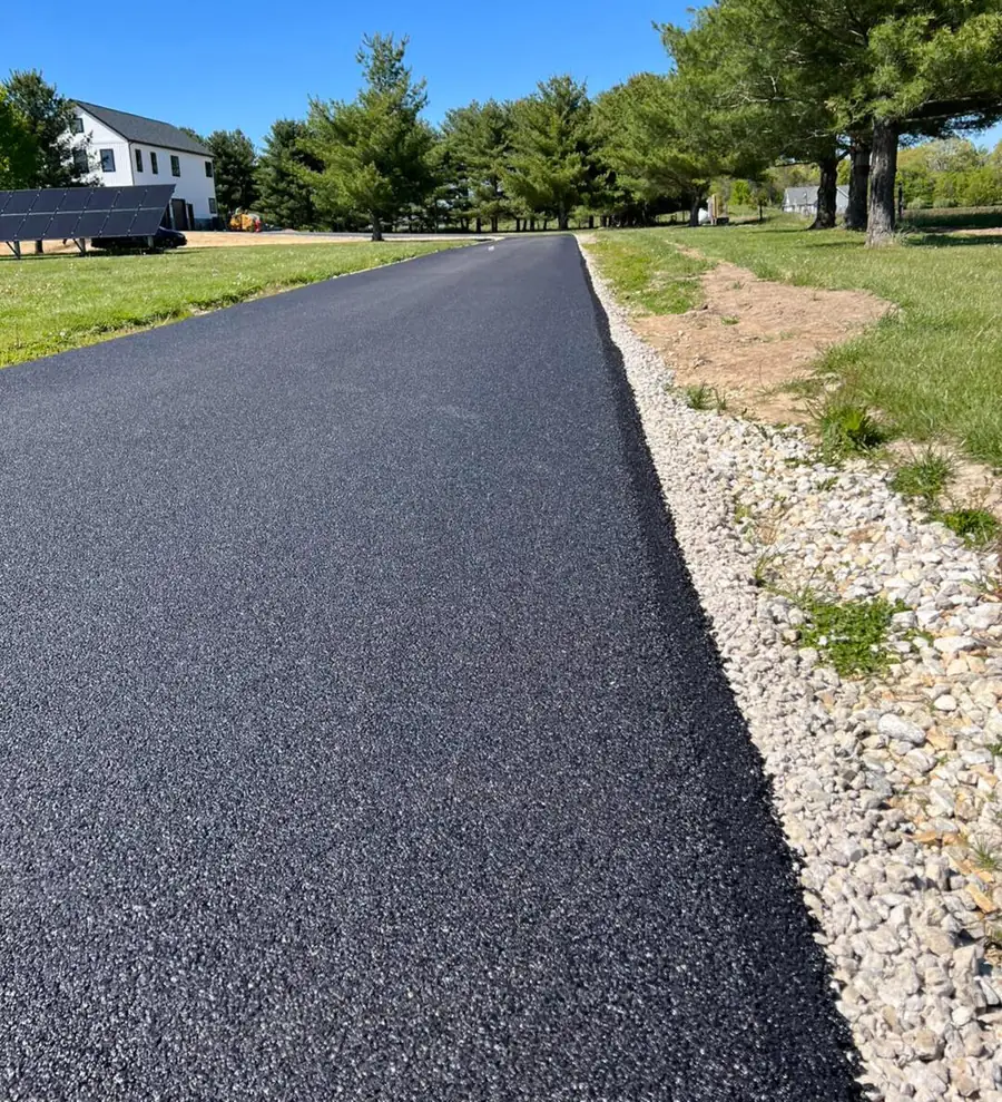 Edge of a newly paved driveway meeting a clean gravel shoulder